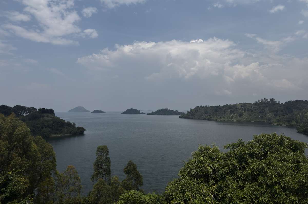a photo of the islands and palm-lined shore of Lake Kivu under a bright sky, Lake Kivu, Rwanda, photo by Next Level of Travel