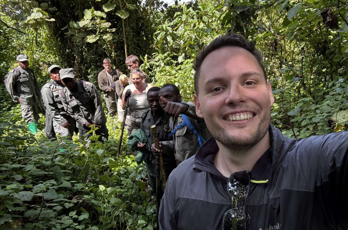 photo of two trekkers pushing through thick green vegetation on a gorilla trek, Volcanoes National Park, Rwanda, photo by Next Level of Travel
