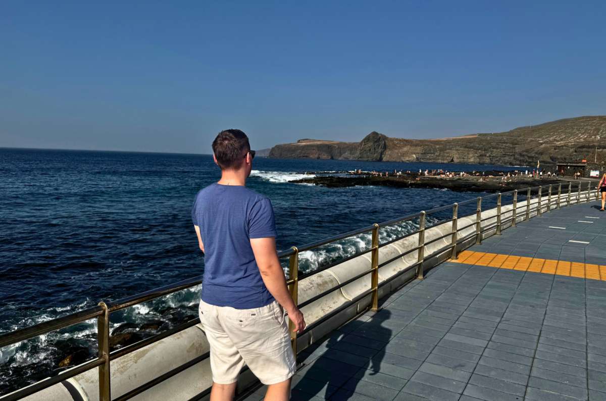 a photo of a tourist looking out over the natural pools of Agaete from the promenade, Gran Canaria, photo by Next Level of Travel