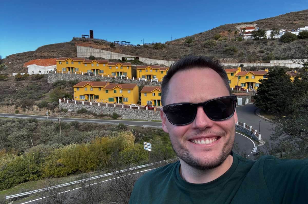 a photo of a tourist with the yellow houses of Artenara in the background, Gran Canaria, photo by Next Level of Travel