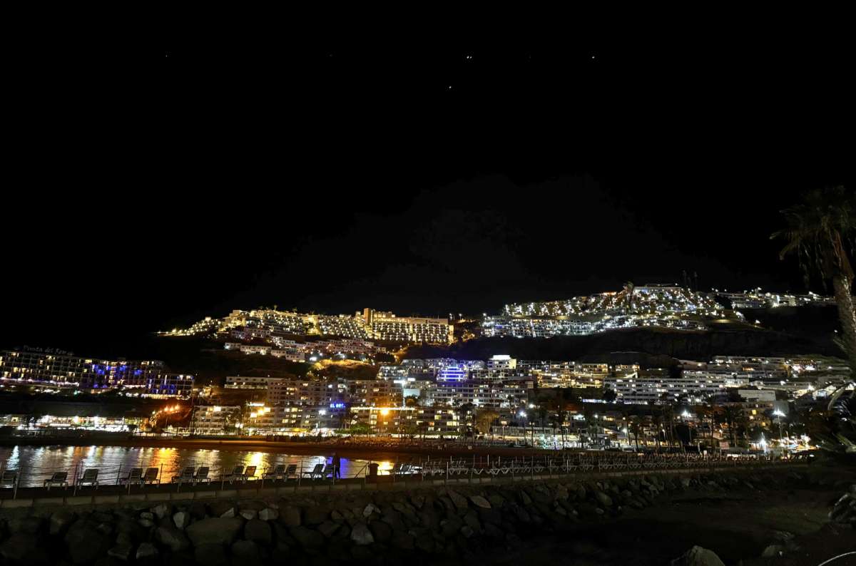 a photo of Puerto Rico de Gran Canaria lit up at night, seen from the beach, photo by Next Level of Travel