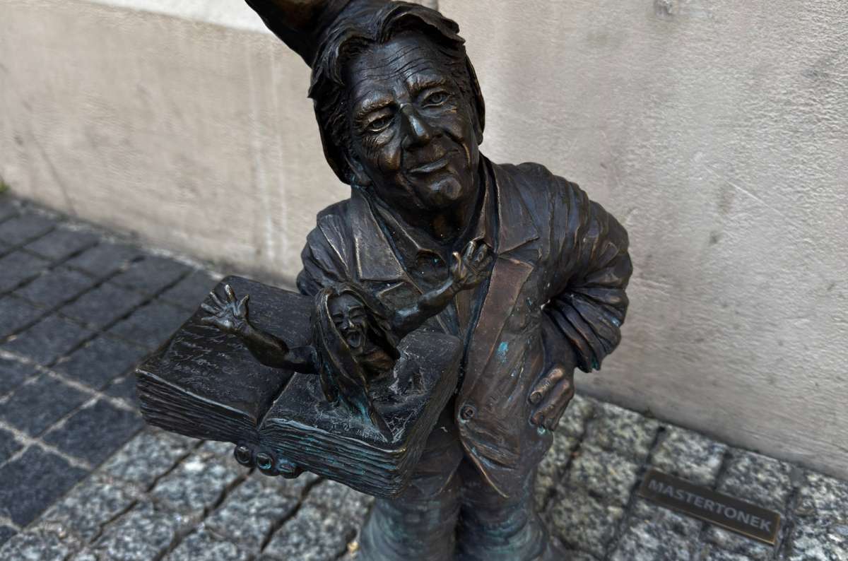 a close-up shot of one of the bronze dwarves in Wroclaw. staring directly into the camera, Poland, photo by Next Level of Travel