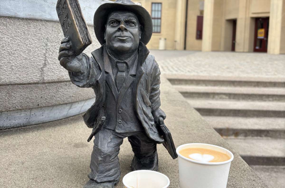 a close-up shot of one of the bronze miniature dwarves next to a coffee cup, Poland, photo by Next Level of Travel