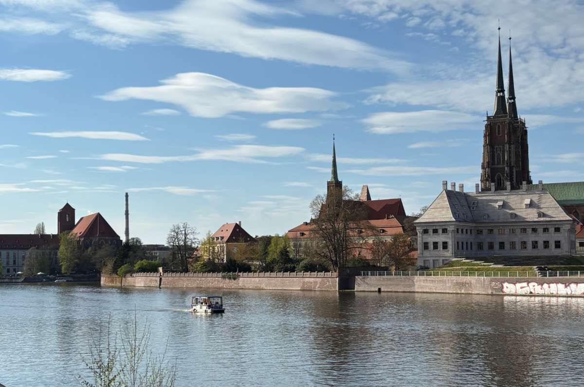 a photo of the Cathedral Island, showing the varius towering monuments in the background and the Oder river in the front, Wroclaw, Poland, photo by Next Level of Travel