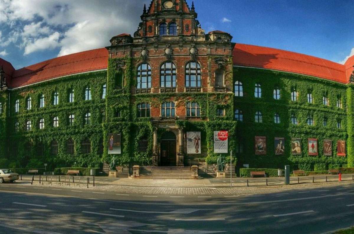 a photo of the exterior of the National Museum in Wroclaw, showong a beautiful building covered in green leaves, Poland