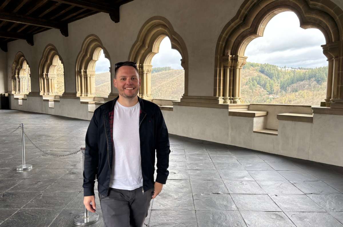 a photo of a tourist standing in the arched gallery overlooking the Our valley, Vianden Castle, Luxembourg, photo by Next Level of Travel