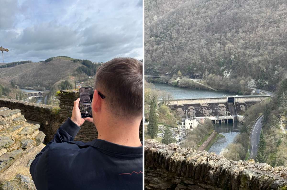 photo of a tourist photographing the valley and the Our river dam with painted mural faces, seen from Vianden Castle, Luxembourg, photo by Next Level of Travel