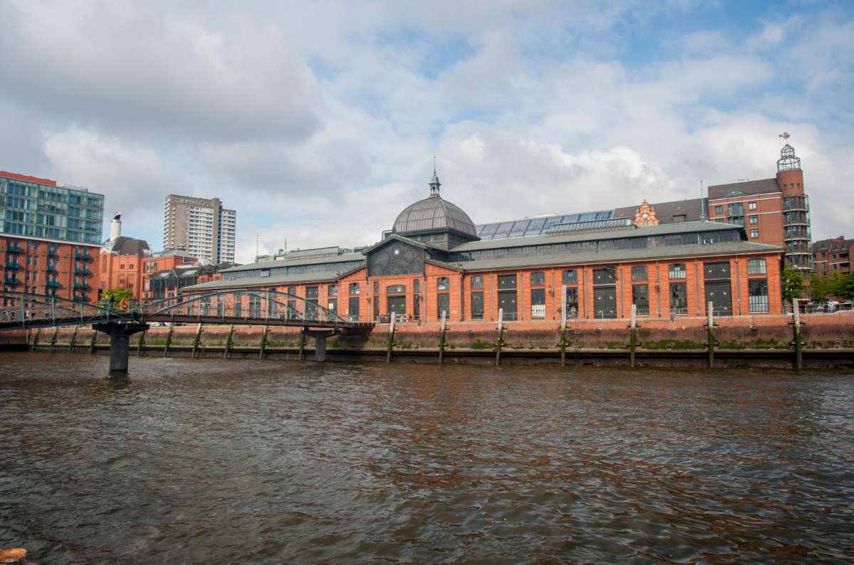 a photo of the Fischmarkt exterior, showing the decorative red buidling surrounded by the river Elbe, Germany