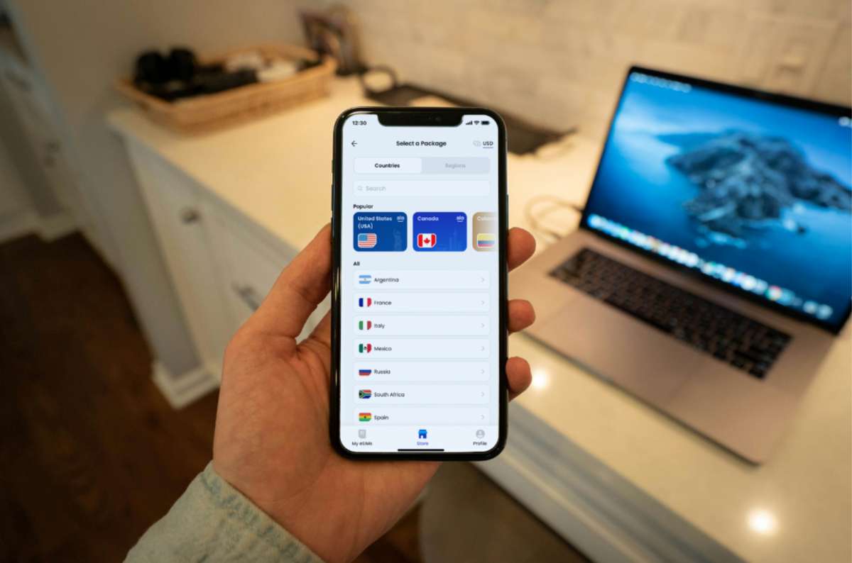 a photo of a hand holding an iPhone showing the aloSIM website with eSIM data packages