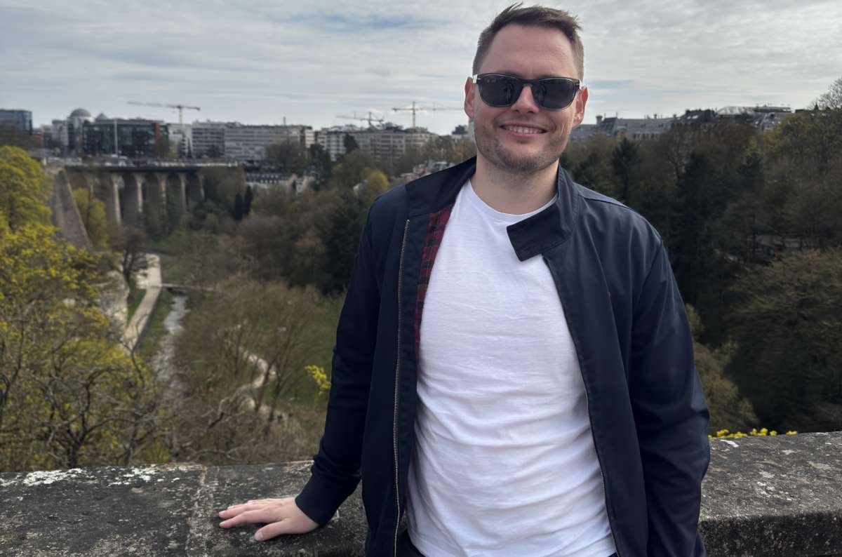 A tourist at a Pétrusse valley viewpoint with the city skyline and the State Savings Bank tower behind, Luxembourg City, Luxembourg, photo by Next Level of Travel