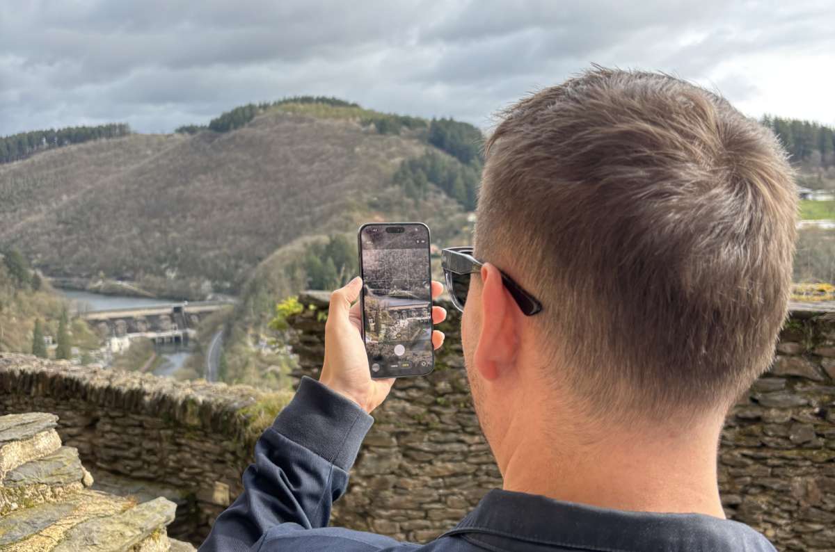 A tourist at a viewpoint with arms raised over the Vianden valley and castle, Vianden, Luxembourg, photo by Next Level of Travel