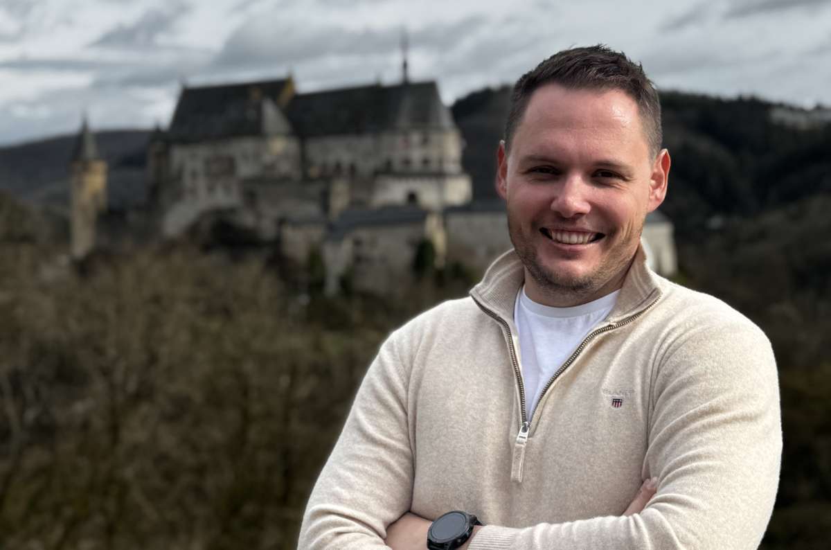 a tourist at a viewpoint with Vianden Castle rising above the valley behind him, Luxembourg, photo by Next Level of Travel