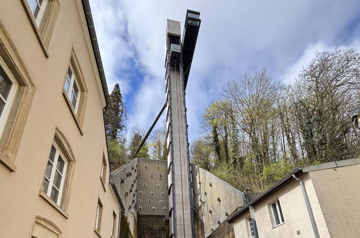 The base of the glass Pfaffenthal panoramic elevator surrounded by other tall building and forests in the bcakground, Luxembourg City, Luxembourg, photo by Next Level of Travel