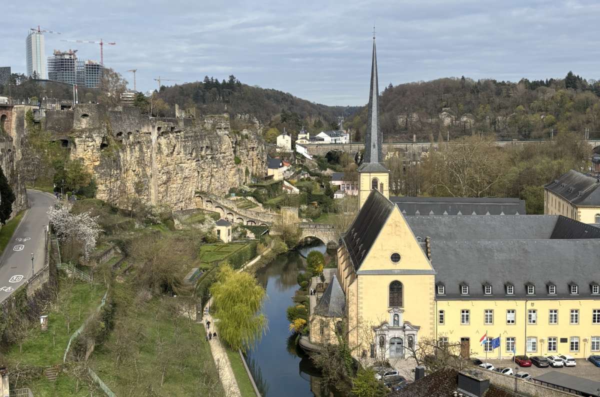 Yellow houses and the Alzette river in the Grund lower town, framed by cliffs, Luxembourg, photo by Next Level of Travel