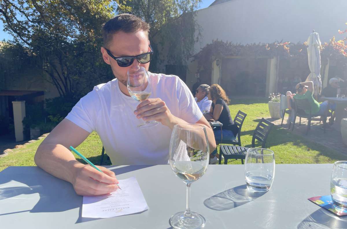 Tourist tasting white wine at a vineyard in Stellenbosch, South Africa, photo by Next Level of Travel