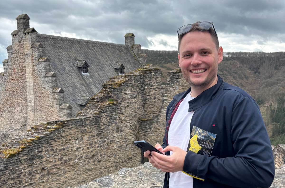 a photo of a tourist checking his phone at a castle overlook, Luxembourg, photo by Next Level of Travel