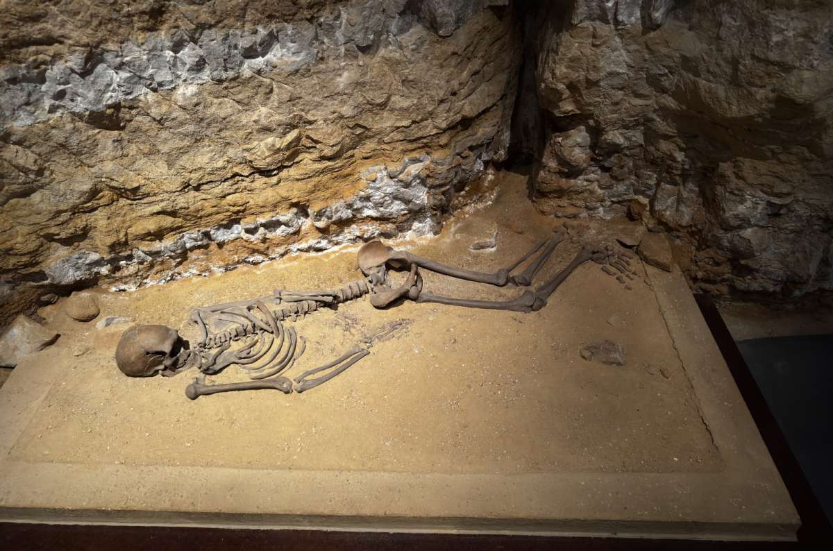a photo of a human skeleton displayed in situ in a sandstone cave archaeological excavation, Luxembourg, photo by Next Level of Travel