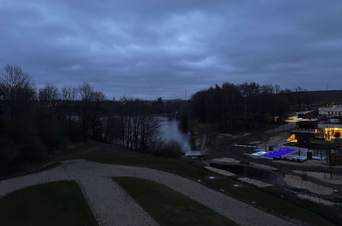 a photo of a luxury hotel resort complex at dusk with a glowing blue outdoor pool and river view in the distance, Luxembourg, photo by Next Level of Travel