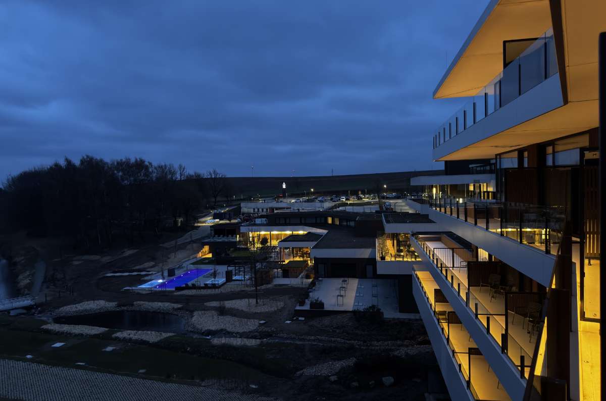 a photo of a modern luxury hotel resort at dusk with illuminated balconies and a glowing blue outdoor pool area, Luxembourg, photo by Next Level of Travel