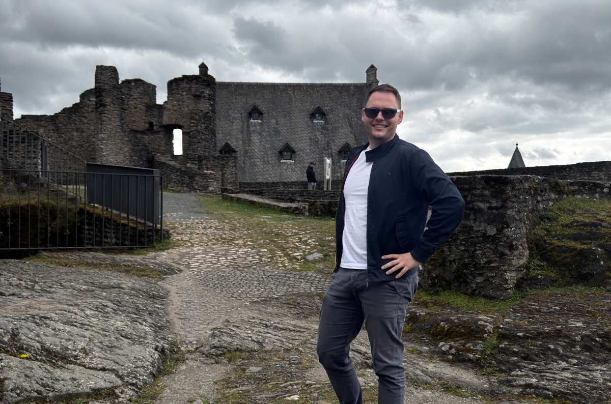 a photo of a tourist posing inside the ruins of Bourscheid Castle, Luxembourg, photo by Next Level of Travel