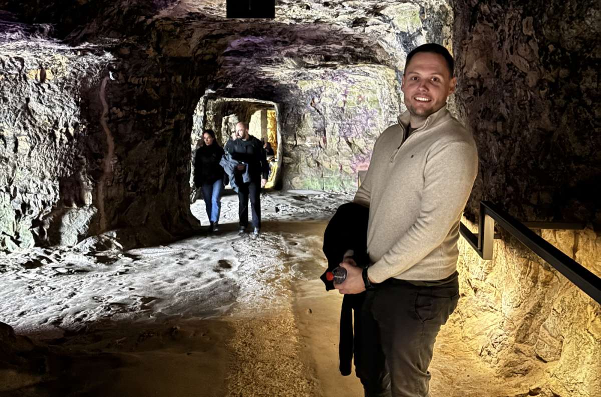 a photo of a tourist smiling inside the underground tunnels of the Bock Casemates with other visitors visible in the background, Luxembourg, photo by Next Level of Travel