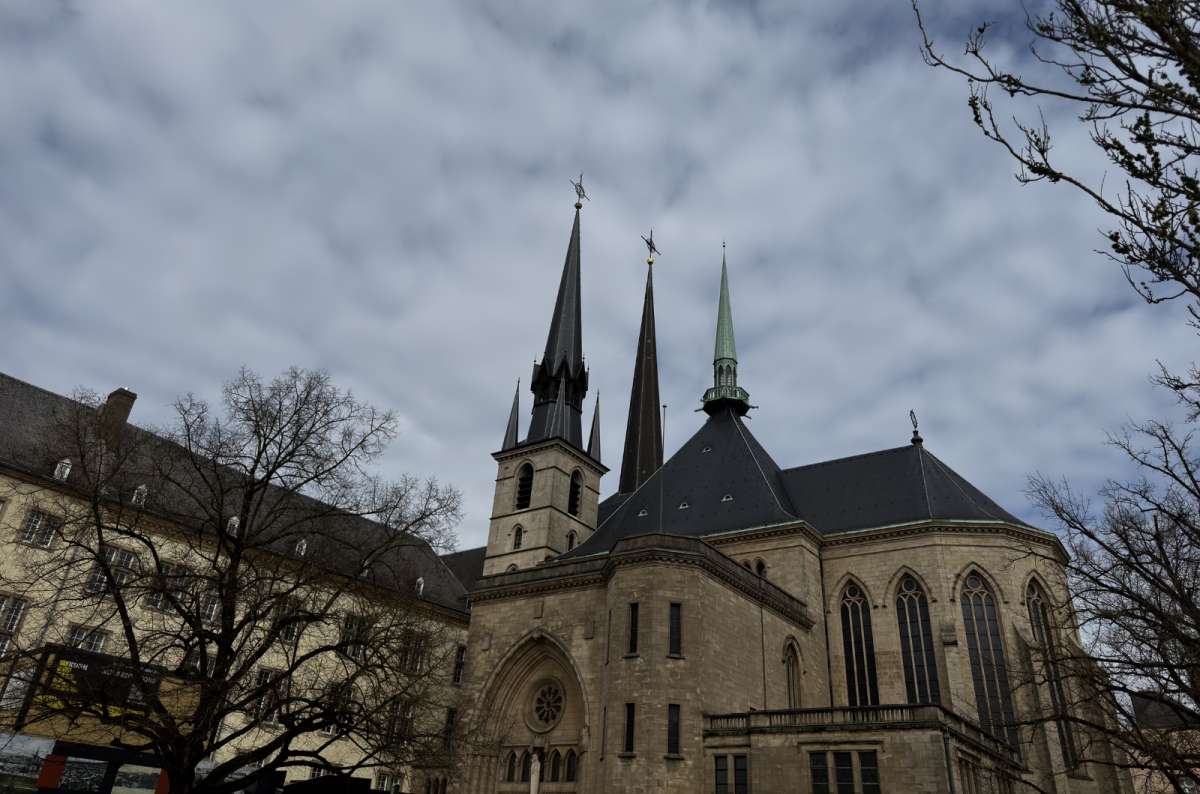 a photo of Notre-Dame Cathedral, showing its cluster of Gothic spires rising above the surrounding buildings, Luxembourg, photo by Next Level of Travel