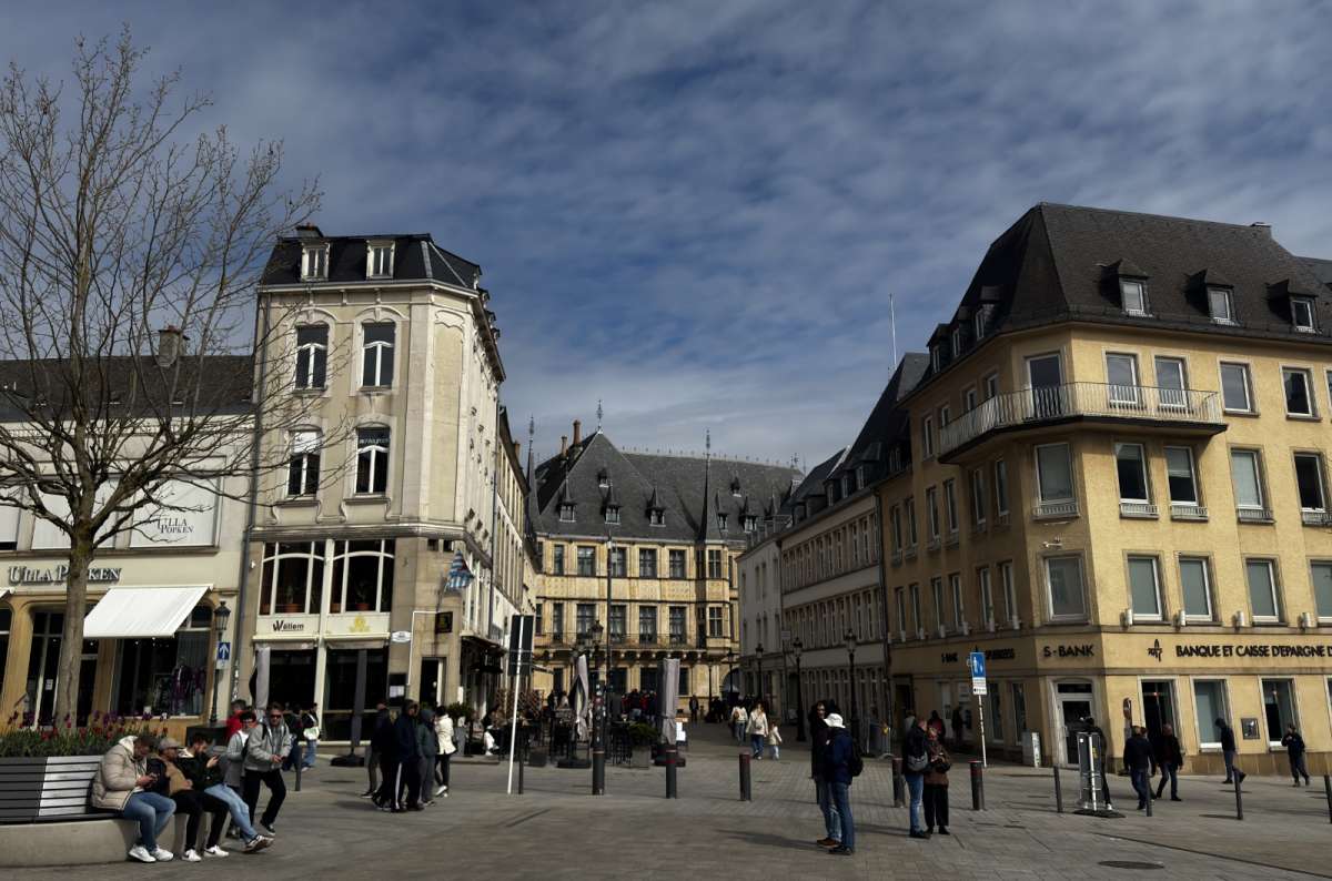 a photo of Place Guillaume II, with people sitting at outdoor cafe terraces and walking through the main public square, Luxembourg, photo by Next Level of Travel