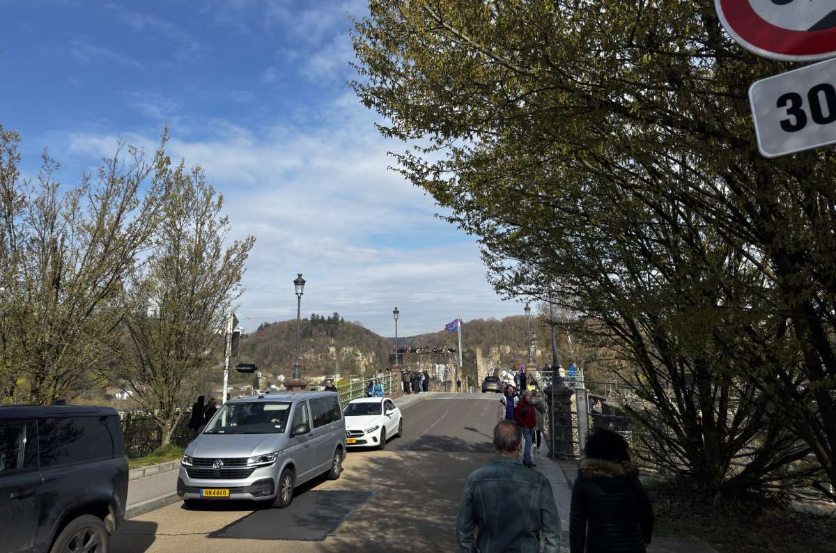 a photo of the main bridge over the river in Luxembourg with cars and pedestrians crossing and the rising on the hillside above, Luxembourg, photo by Next Level of Travel