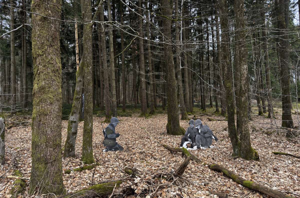 a photo of the Schumannseck Memorial Trail, with life-size photographic installations of WWII soldiers positioned among the trees, Luxembourg, photo by Next Level of Travel
