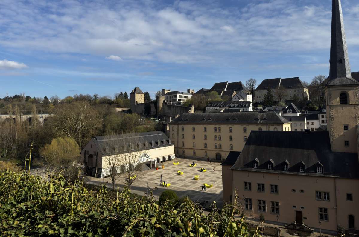 a photo of the view of the Neumunster Abbey and the Grund below the old town cliffs, with the railway viaduct visible across the valley, Luxembourg, photo by Next Level of Travel