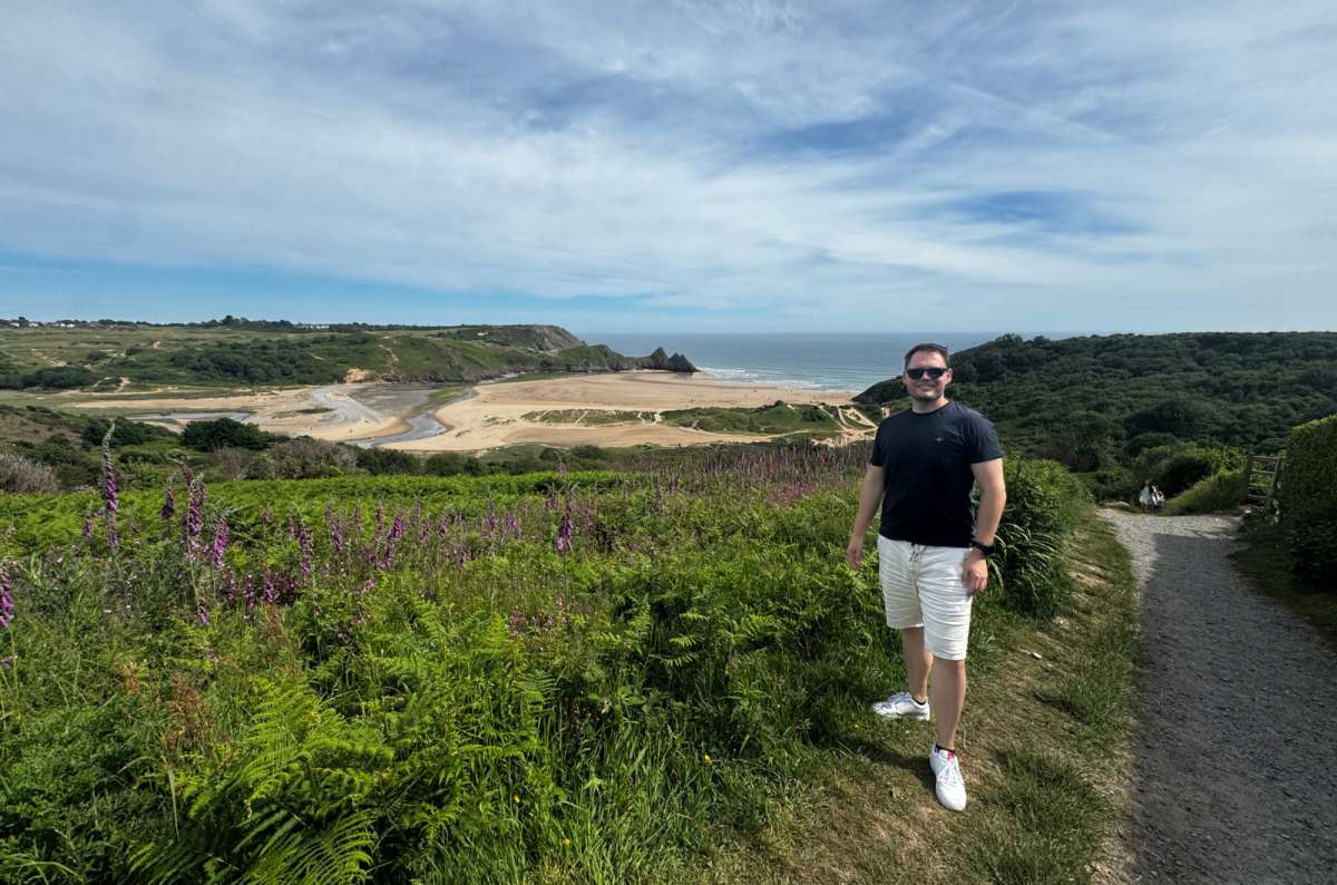 a diptych photo of a tourist barefoot on Three Cliffs Bay beach on the left and the view over the bay past purple foxgloves on the right, Gower Peninsula, Wales, photo by Next Level of Travel