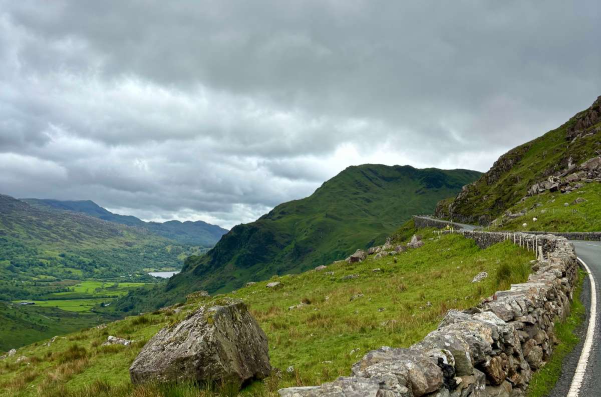 a photo of a mountain pass road winding through a green valley in Eryri National Park, near Llanberis, Wales, photo by Next Level of Travel