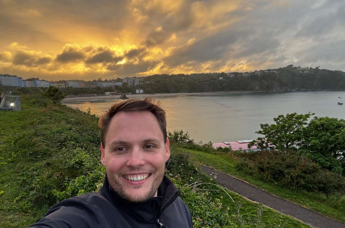 a photo of a tourist at golden hour above the bay and colourful houses of Tenby, Tenby, Wales, photo by Next Level of Travel