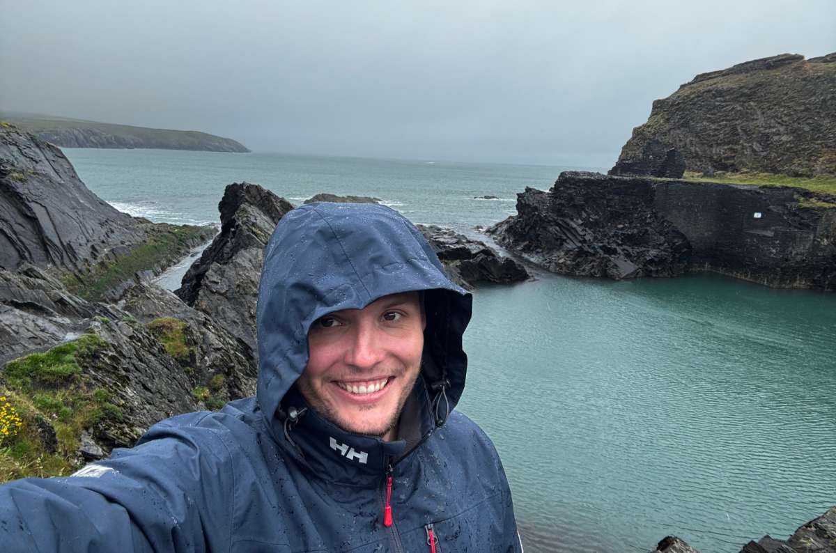 a photo of a tourist in a rain jacket above the turquoise water of the Blue Lagoon at Abereiddy on the Pembrokeshire coast, Abereiddy, Wales, photo by Next Level of Travel