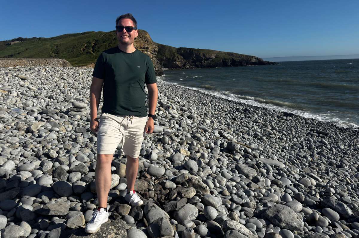 a photo of a tourist on the pebble beach of a cove backed by cliffs on the Glamorgan Heritage Coast, Dunraven Bay, Wales, photo by Next Level of Travel