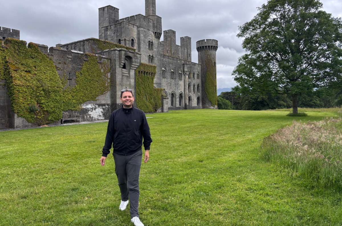 a photo of a tourist walking the lawn before the ivy-clad towers of Penrhyn Castle, near Bangor, Wales, photo by Next Level of Travel