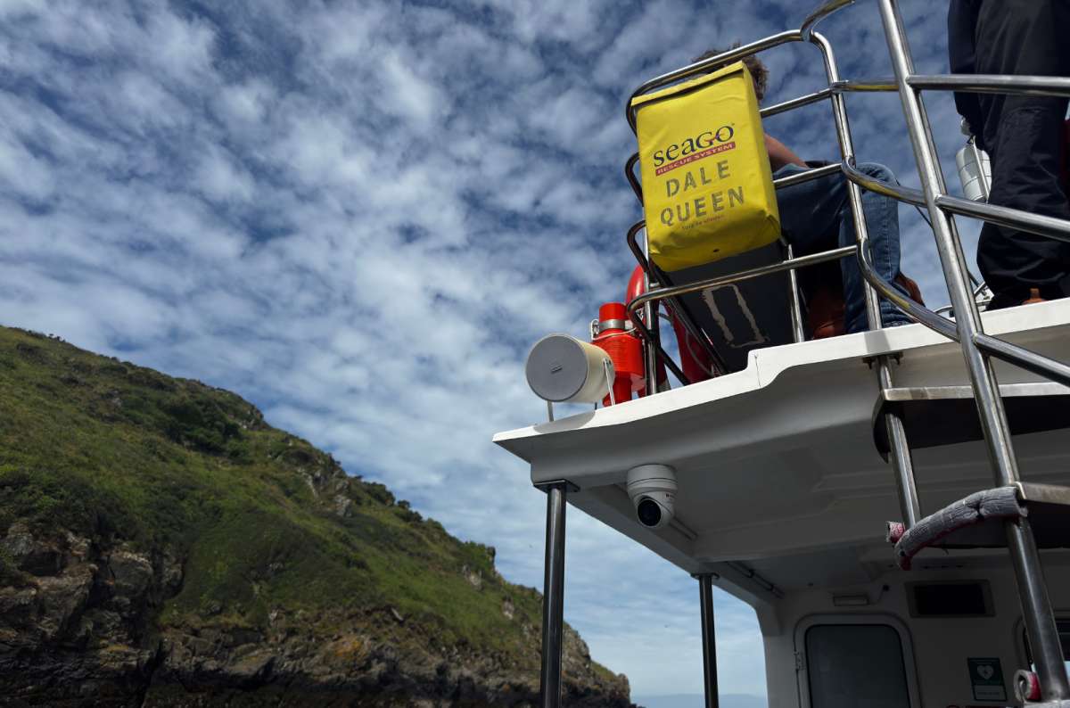 a photo of the Dale Queen tour boat passing a steep green headland on the crossing to Skomer Island, Pembrokeshire, Wales, photo by Next Level of Travel