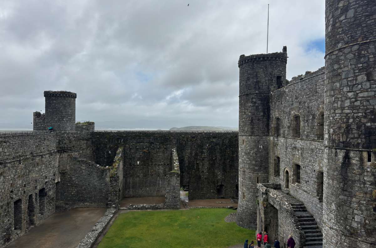 a photo of the round towers and green inner ward of Harlech Castle with the coast beyond, Harlech, Wales, photo by Next Level of Travel