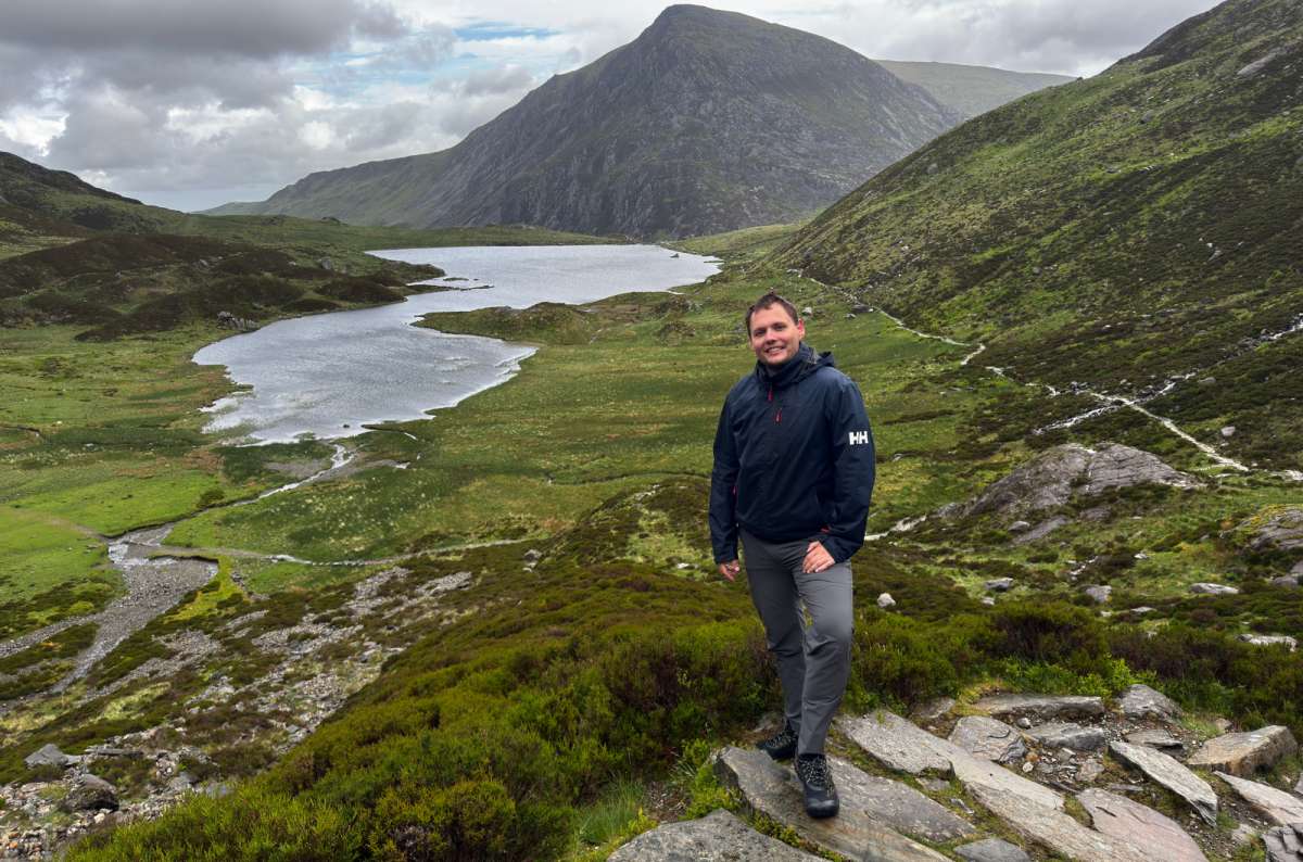 a tourist posing in fron of Cwm Idwal, surrounded by nature on a cold rainy day, Wales, photo by Next Level of Travel
