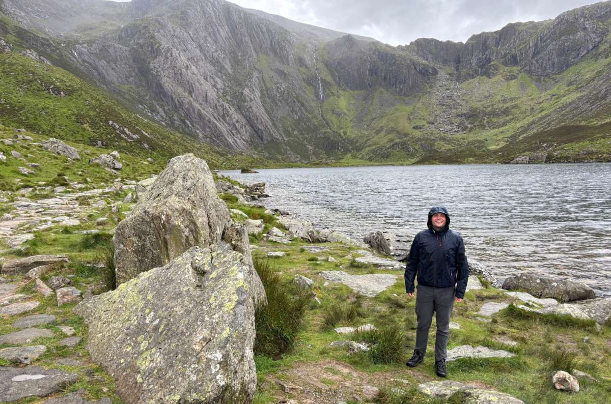 a tourist posing in fron of Cwm Idwal, surrounded by nature on a cold rainy day, Wales, photo by Next Level of Travel