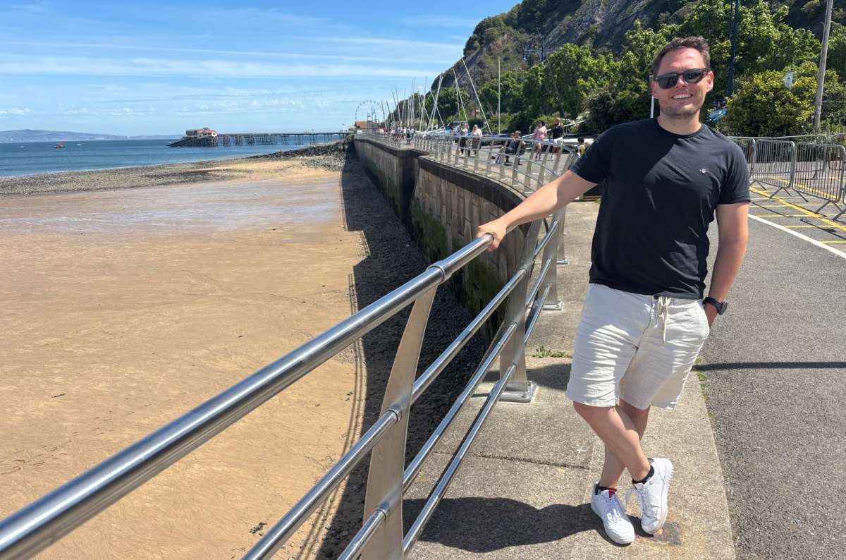 a tourist posing in fron of the sea at Swansea on a sunny day, Wales, photo by Next Level of Travel