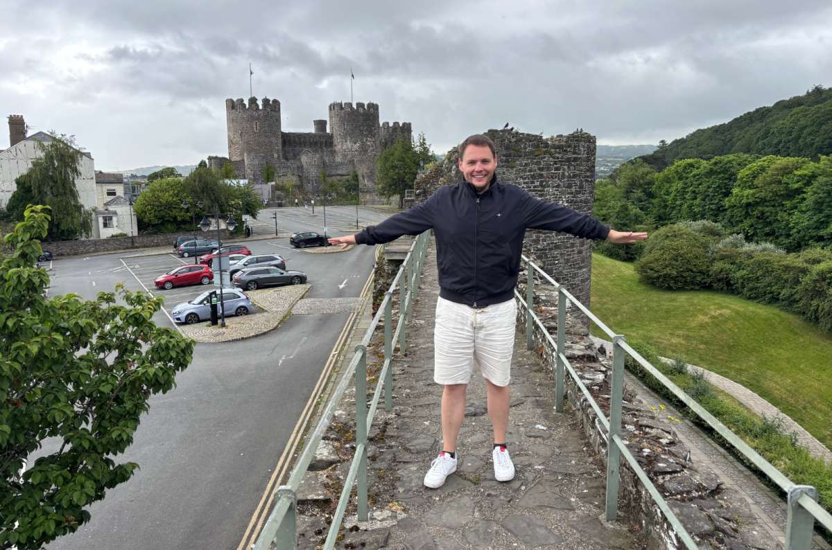 a photo of a tourist on the medieval town walls of Conwy with the castle behind, Conwy, Wales, photo by Next Level of Travel