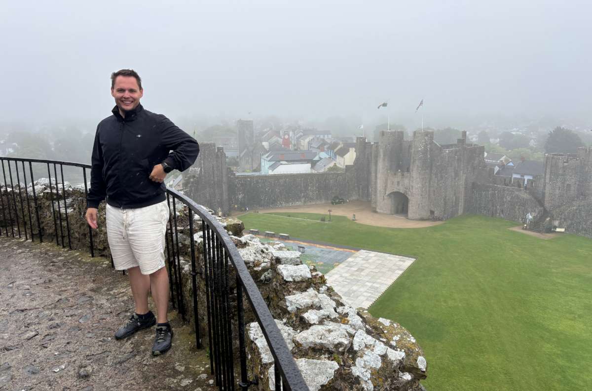 a photo of a tourist on the walls of Pembroke Castle above the town in the mist, Pembroke, Wales, photo by Next Level of Travel