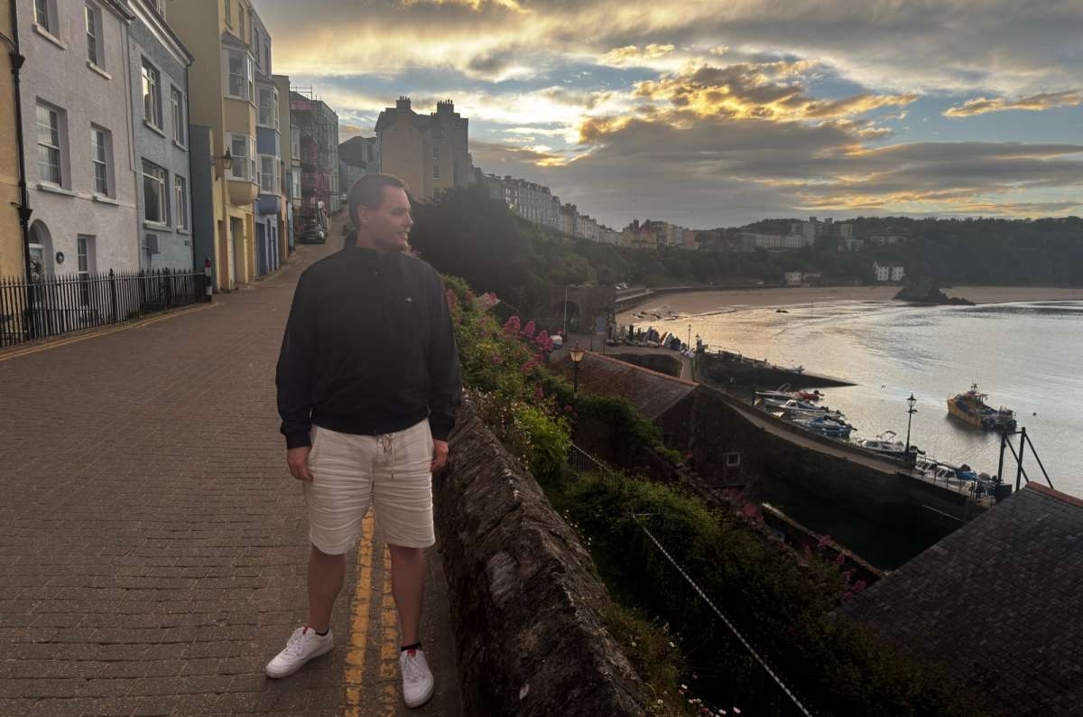 a photo of a tourist strolling above Tenby harbour and its colourful houses at sunset, Tenby, Wales, photo by Next Level of Travel