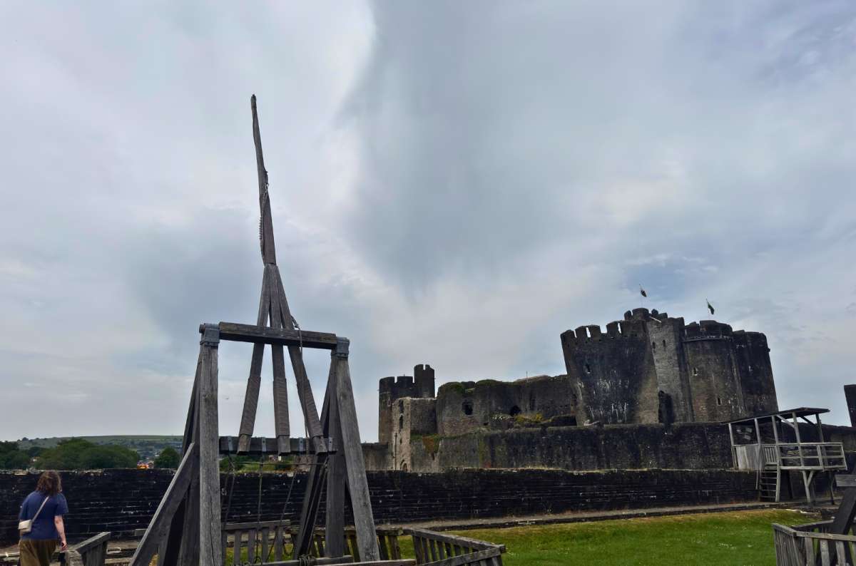 a photo of a wooden siege engine on the walls of Caerphilly Castle with the fortress behind, Caerphilly, Wales, photo by Next Level of Travel