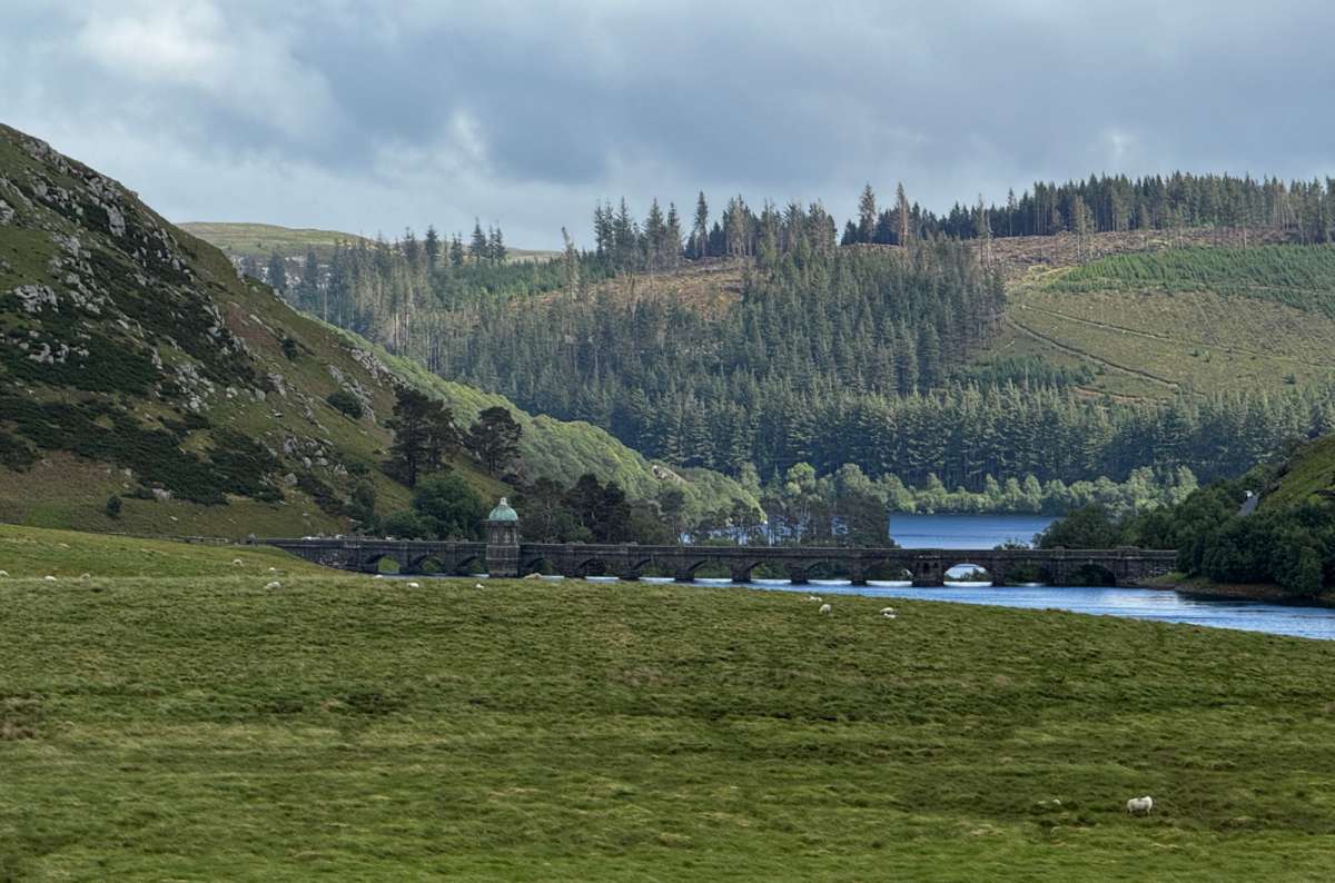 a photo of the domed valve tower and stone viaduct crossing an Elan Valley reservoir with sheep on the hillside, Elan Valley, Wales, photo by Next Level of Travel