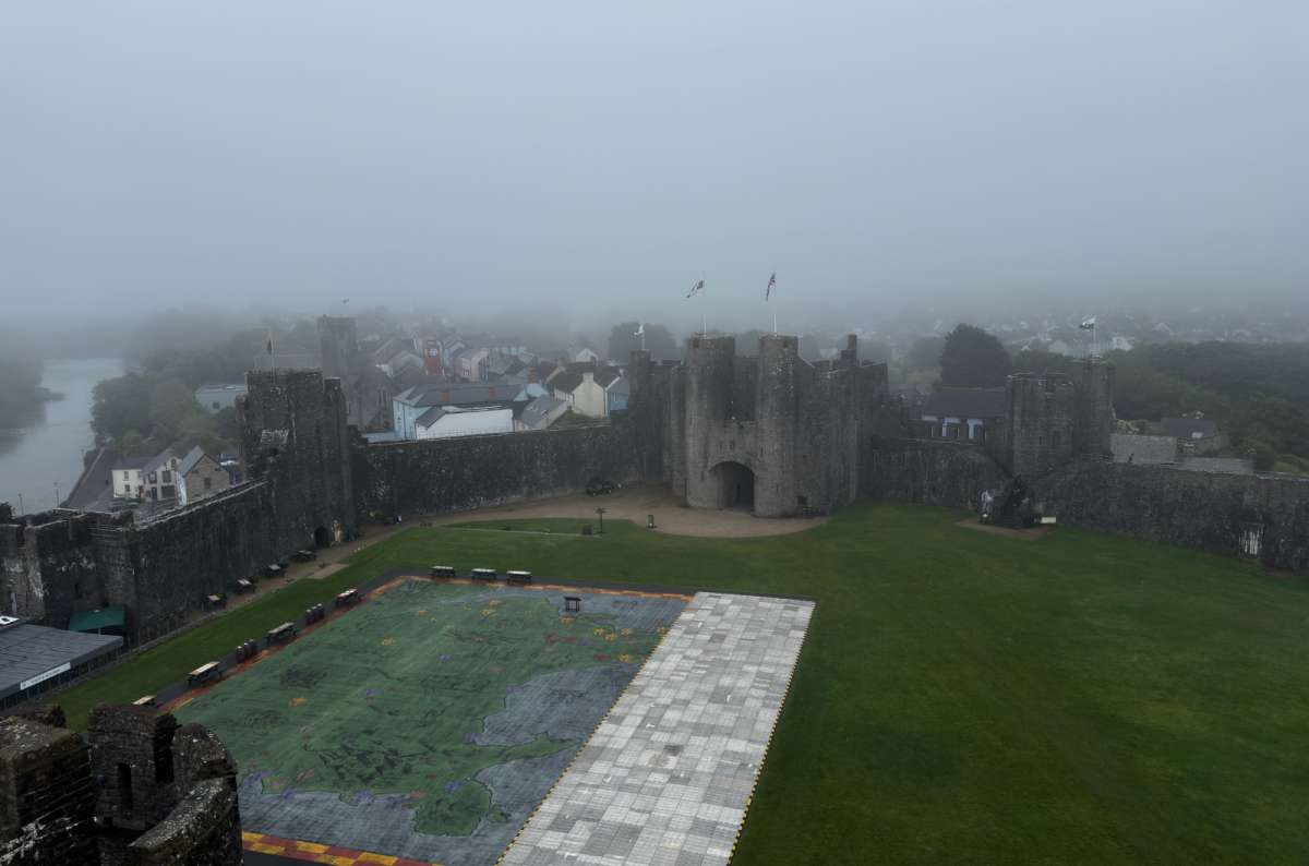 a photo of the misty inner ward of Pembroke Castle with a large map of Wales laid on the ground and the gatehouse beyond, Pembroke, Wales, photo by Next Level of Travel