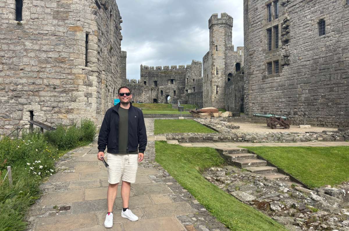 a photo of a tourist standing in the courtyard at Caernarfon Castle, Wales, photo by Next Level of Travel