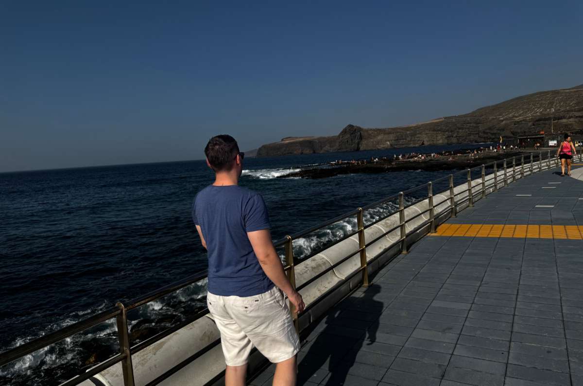 a photo of a tourist looking out over the Atlantic from the Agaete seafront promenade toward a distant headland, Canary Islands, photo by Next Level of Travel