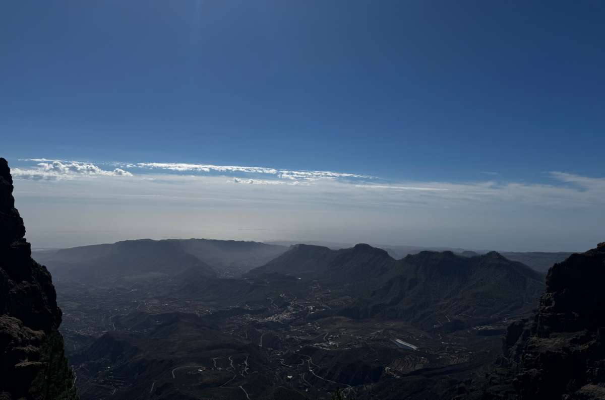 a photo of hazy ridges and a valley fading toward the sea under a pale sky from a high mountain viewpoint, Canary Islands, photo by Next Level of Travel
